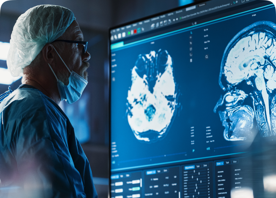 Doctor analyzing brain scans on large monitor.